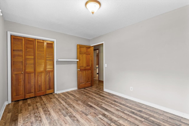 unfurnished bedroom featuring a textured ceiling, a closet, and wood-type flooring