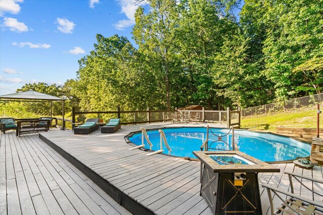 view of swimming pool featuring an outdoor hangout area, a hot tub, a deck, and a gazebo