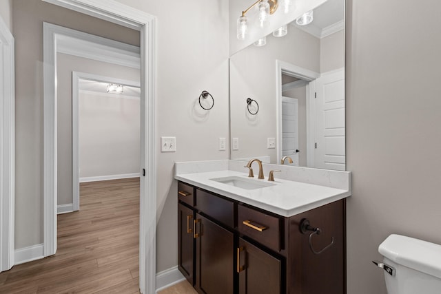 bathroom featuring hardwood / wood-style flooring, toilet, vanity, and ornamental molding