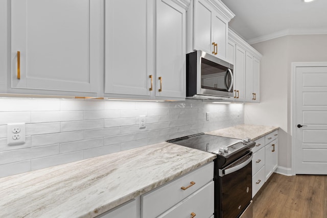 kitchen featuring light stone countertops, hardwood / wood-style floors, white cabinetry, stainless steel appliances, and ornamental molding