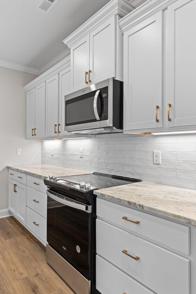 kitchen with white cabinets, stainless steel appliances, and light hardwood / wood-style flooring