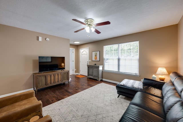 living room with a textured ceiling, ceiling fan, and dark hardwood / wood-style floors