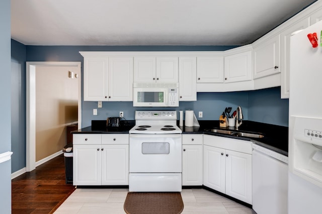 kitchen with light wood-type flooring, white appliances, sink, and white cabinets