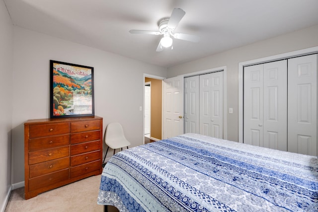 bedroom with two closets, ceiling fan, and light carpet