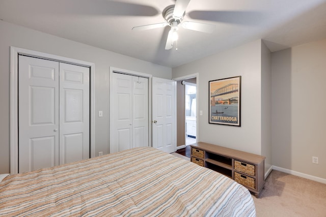 bedroom featuring ceiling fan, light colored carpet, and multiple closets