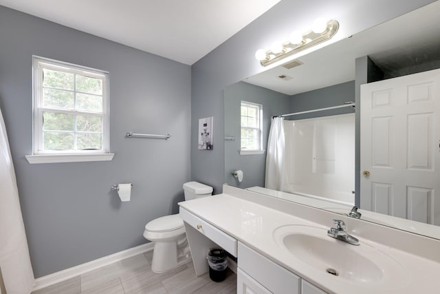 bathroom featuring vanity, toilet, walk in shower, and a healthy amount of sunlight