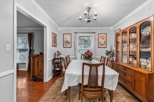 dining space featuring dark wood-type flooring, a notable chandelier, and ornamental molding