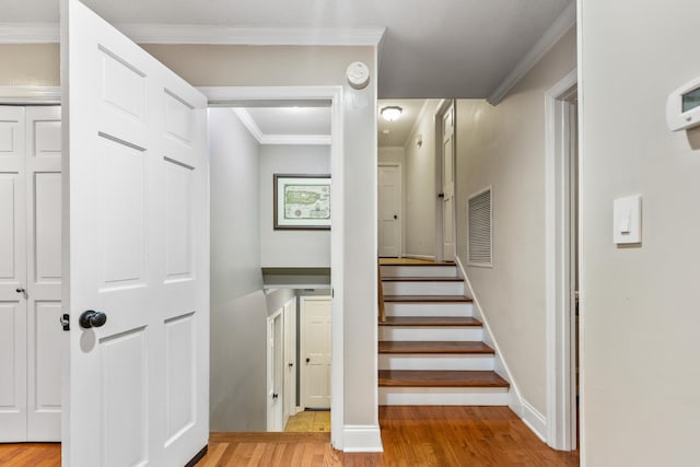 stairway with wood-type flooring and crown molding