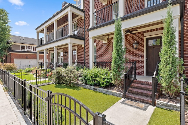 exterior space featuring ceiling fan, a balcony, and a front yard