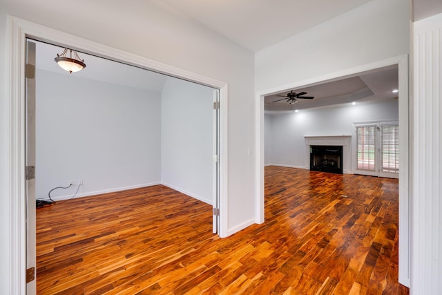 unfurnished living room featuring a tray ceiling, hardwood / wood-style floors, and ceiling fan