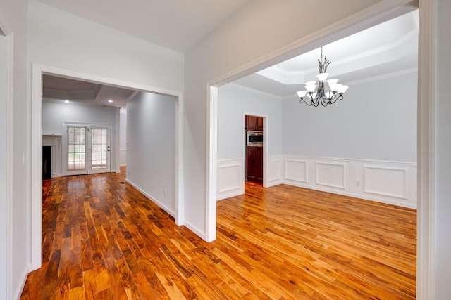 unfurnished room with crown molding, french doors, hardwood / wood-style flooring, and a notable chandelier