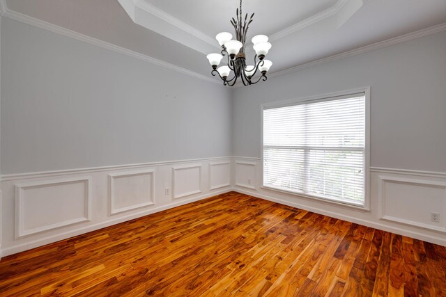 unfurnished room with a tray ceiling, ornamental molding, hardwood / wood-style floors, and a chandelier