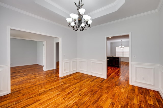 empty room featuring crown molding, hardwood / wood-style floors, and a notable chandelier