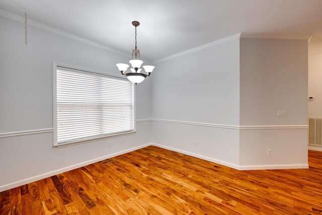 empty room featuring ornamental molding, hardwood / wood-style floors, and a chandelier