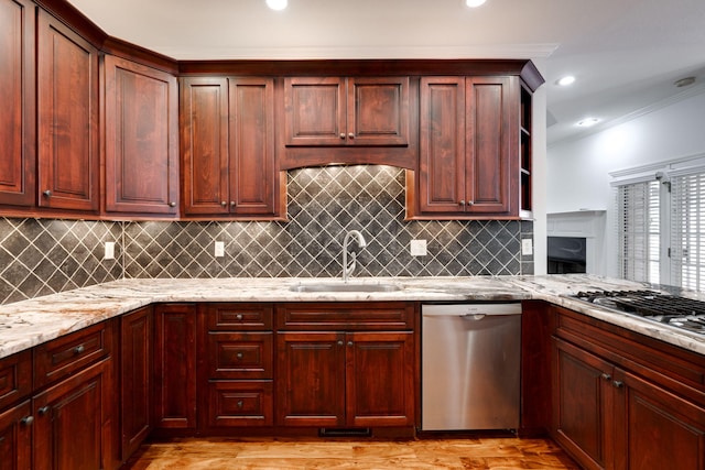 kitchen with ornamental molding, stainless steel appliances, sink, light stone countertops, and light hardwood / wood-style floors