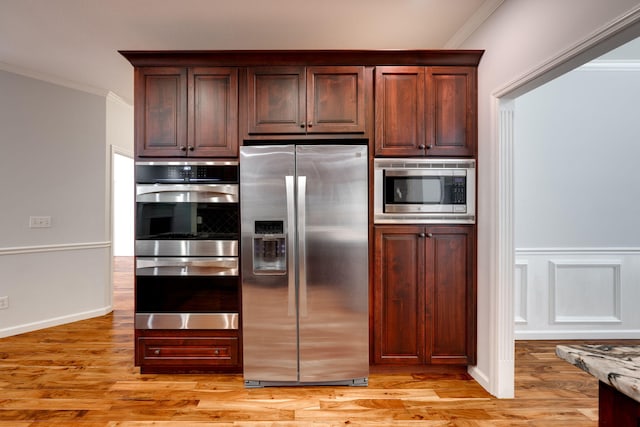 kitchen with appliances with stainless steel finishes, light hardwood / wood-style floors, and crown molding