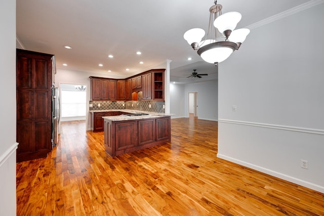 kitchen featuring ceiling fan with notable chandelier, light wood-type flooring, crown molding, and hanging light fixtures