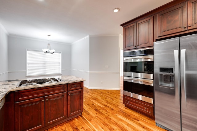 kitchen featuring light hardwood / wood-style flooring, stainless steel appliances, ornamental molding, a chandelier, and light stone counters