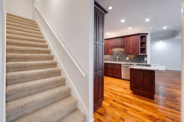 kitchen featuring dishwasher, light hardwood / wood-style flooring, light stone counters, sink, and decorative backsplash