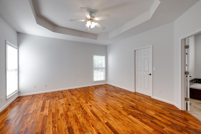 unfurnished bedroom featuring a tray ceiling, wood-type flooring, and ceiling fan