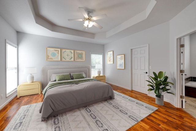 bedroom featuring a tray ceiling, wood-type flooring, and ceiling fan