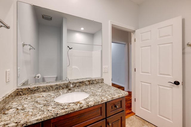 bathroom with a shower, toilet, hardwood / wood-style flooring, and vanity