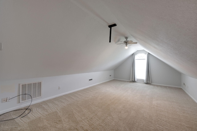 additional living space featuring ceiling fan, light colored carpet, a textured ceiling, and vaulted ceiling