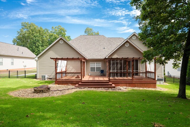 back of house with a lawn, a fire pit, a sunroom, and a deck