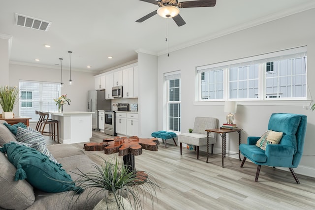 living room with light wood-type flooring, crown molding, and ceiling fan