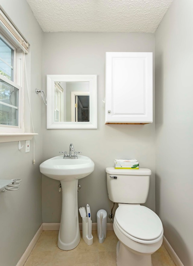 bathroom with tile patterned flooring, a textured ceiling, and toilet