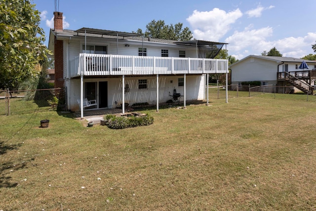 rear view of house with a lawn, a wooden deck, and a patio area