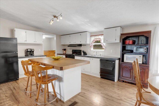 kitchen with a textured ceiling, black appliances, white cabinetry, and light hardwood / wood-style floors