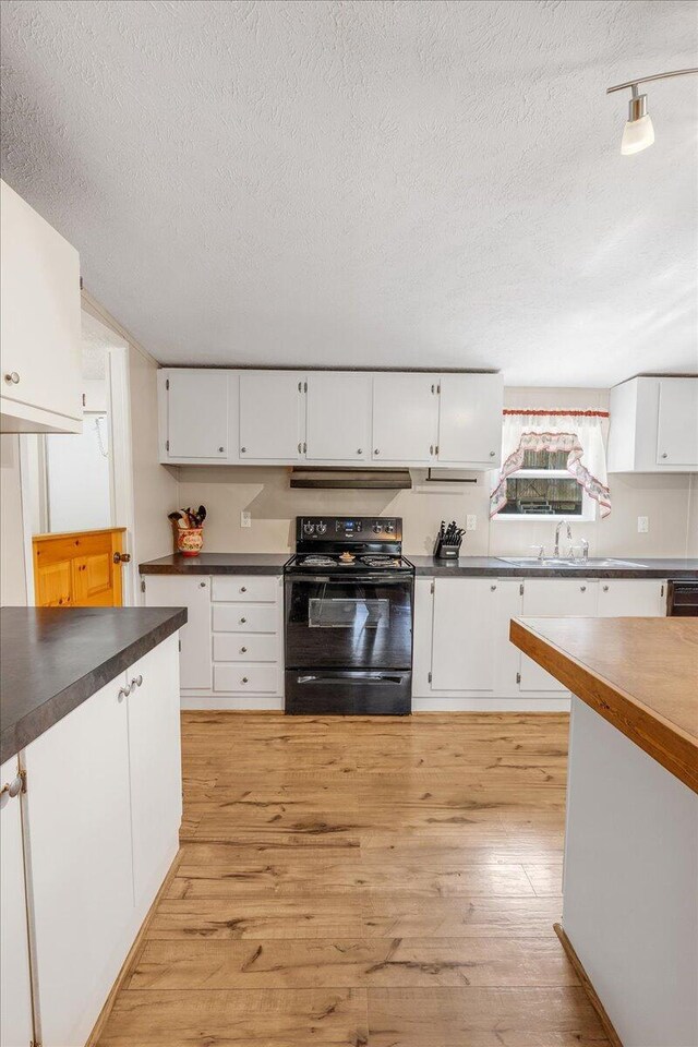 kitchen featuring light wood-type flooring, white cabinets, electric range, and a textured ceiling