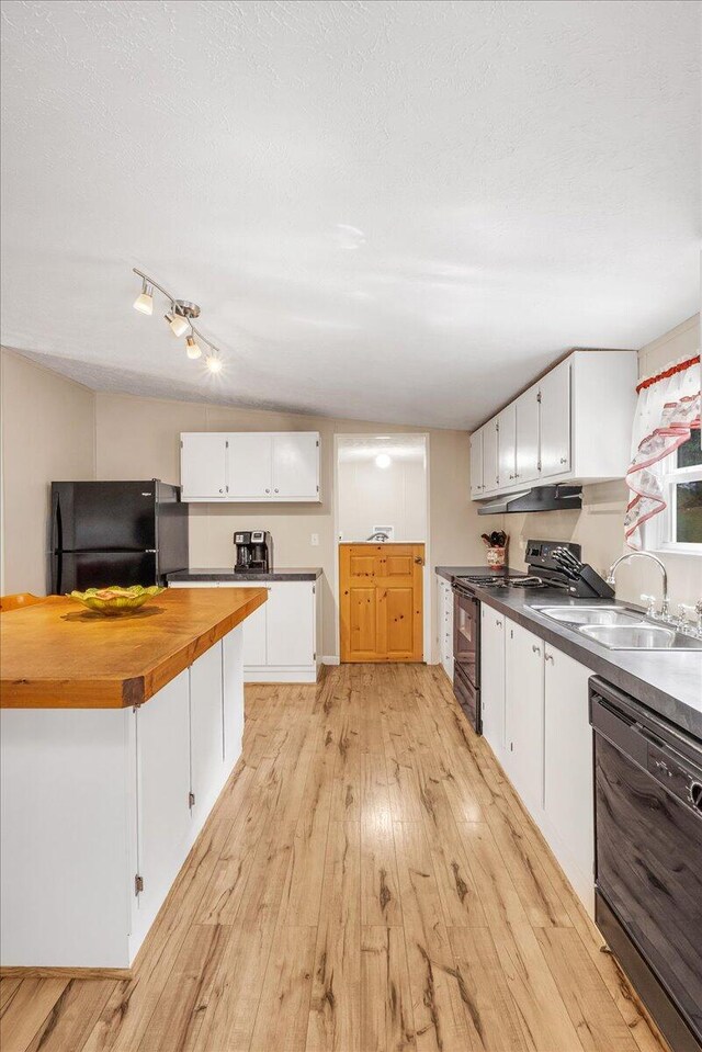 kitchen featuring vaulted ceiling, light wood-type flooring, white cabinetry, sink, and black appliances