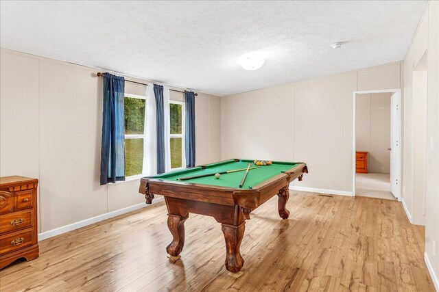 recreation room featuring light wood-type flooring, pool table, and a textured ceiling