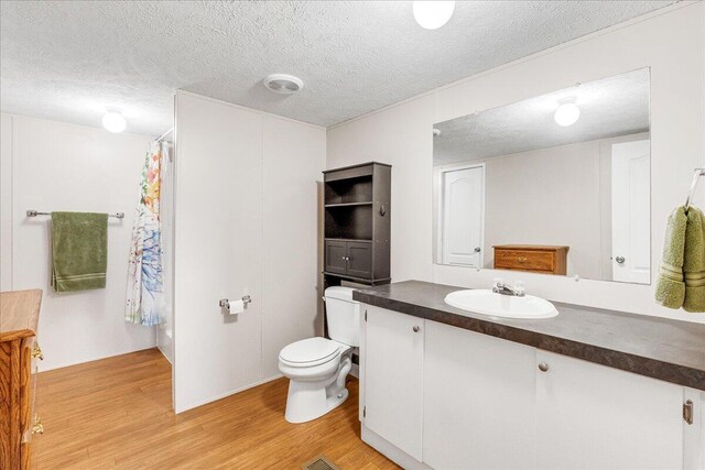 bathroom with toilet, hardwood / wood-style flooring, a textured ceiling, and vanity