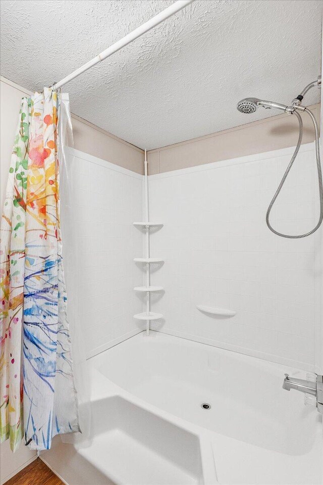 bathroom with wood-type flooring, shower / bath combo with shower curtain, and a textured ceiling