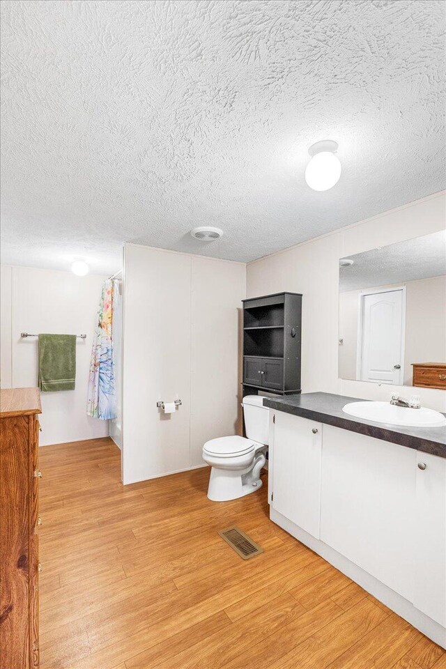 bathroom with toilet, hardwood / wood-style flooring, and vanity