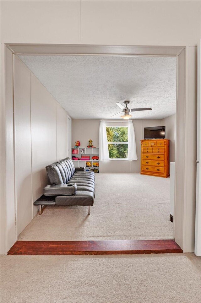 carpeted living room with a textured ceiling and ceiling fan