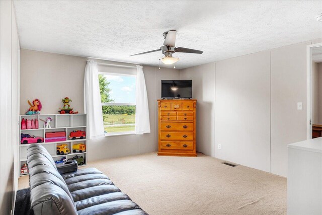 carpeted living room with a textured ceiling and ceiling fan