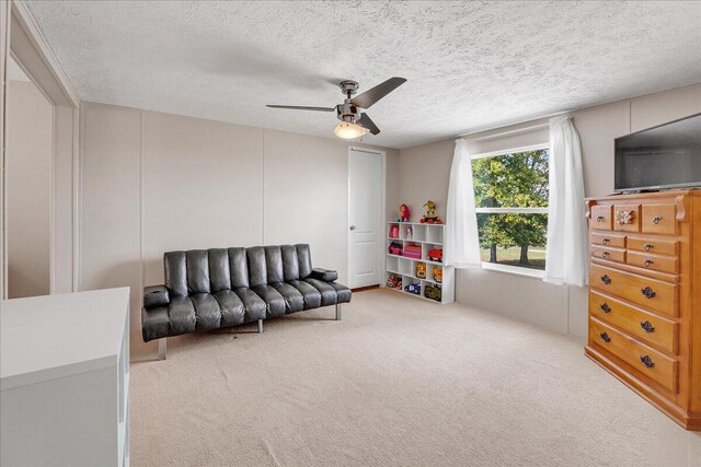 living area featuring a textured ceiling, ceiling fan, and carpet flooring