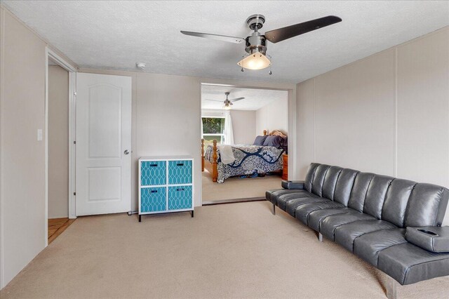 carpeted living room featuring a textured ceiling and ceiling fan