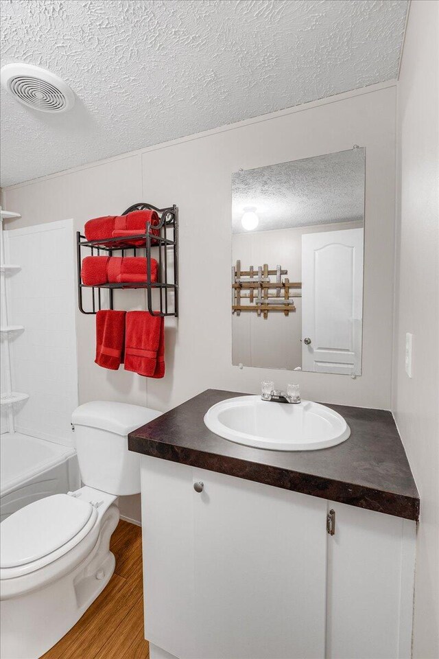 full bathroom featuring a textured ceiling, vanity, toilet, and hardwood / wood-style flooring