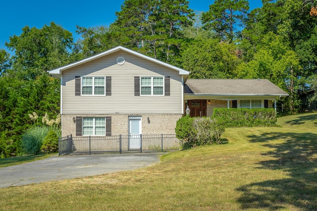 tri-level home with brick siding, a front lawn, and fence