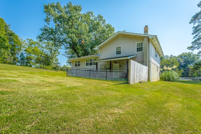 back of property with ceiling fan and a lawn