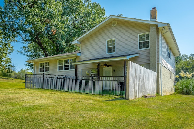 back of house with ceiling fan and a lawn