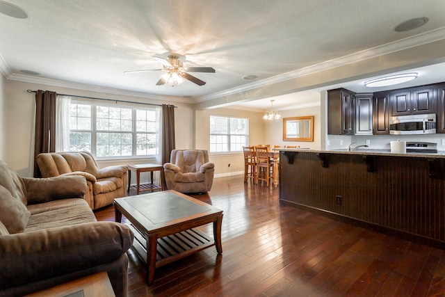 living room featuring ceiling fan with notable chandelier, dark wood-type flooring, a textured ceiling, and ornamental molding