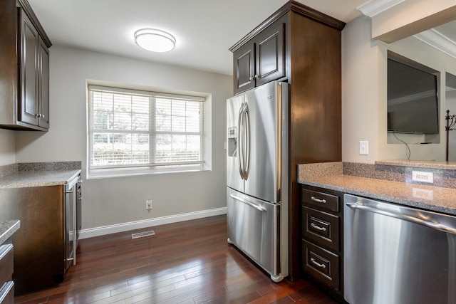 kitchen featuring crown molding, stainless steel appliances, light stone counters, dark hardwood / wood-style floors, and dark brown cabinetry