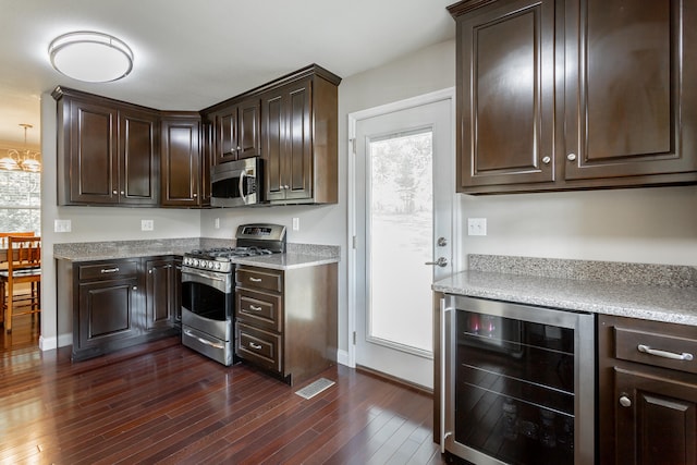 kitchen featuring appliances with stainless steel finishes, dark brown cabinets, beverage cooler, and dark wood-type flooring