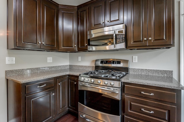 kitchen featuring dark brown cabinets, stainless steel appliances, and light stone countertops